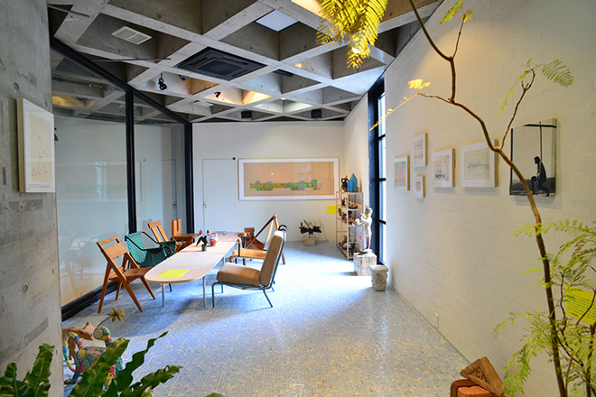 リビングルームの一部が再現された会場風景（3階）。リナ自らデザインした椅子の数々が展示され、工芸品や民芸品も並ぶ。床は淡いブルーを基調にしたガラスモザイクタイル。