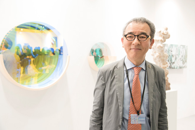 アートフェア東京実行委員会の理事で「東京画廊＋BTAP」の山本豊津氏。シムラブロスの鏡とガラスの作品の前で。