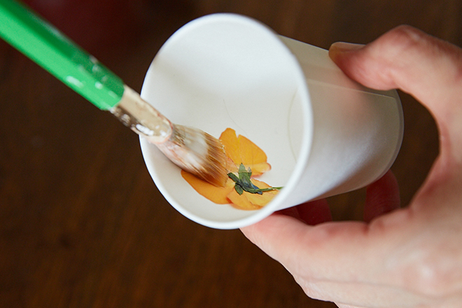 溶かしたろうを平筆にとり、紙コップの内側に押し花を押さえるようにして 上からろうを塗って貼りつける。その後、全体にろうを流し込むことで、 表面に花が浮かび上がる。