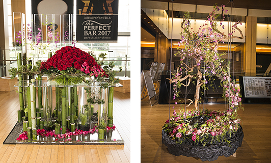 （左）優良賞『この時を この場所で』／のりえ 真紅と濃ピンクのバラが映える。生花と花弁の組み合わせが華やかに時の流れを感じさせ、青竹と松という日本的な要素は、日本の文化やアート、デザインを発信しながら10周年を迎えた東京ミッドタウンへの祝賀にも通じる印象。 （右）優良賞『The Confluence』／YUICHI YOSHIMOTO 宙に浮いた流木にからまりながら、上へ伸びていくような息吹が感じられる作品。淡めの色合いのバラと、ヒラヒラと舞うようにアレンジされた花びらが可憐な雰囲気を醸し出していた。